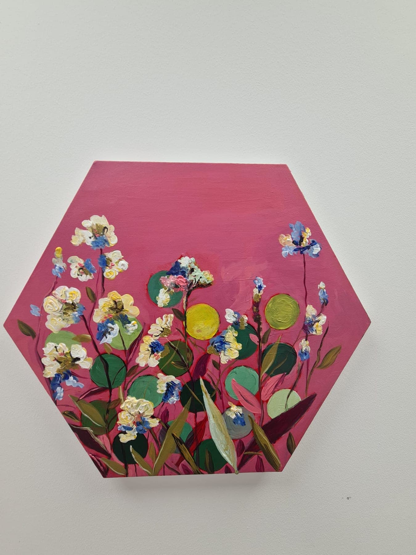A hexagonal panel painted deep magenta, carrying a spray of white and yellow flowers modelled in thick relief so they stand off the surface.